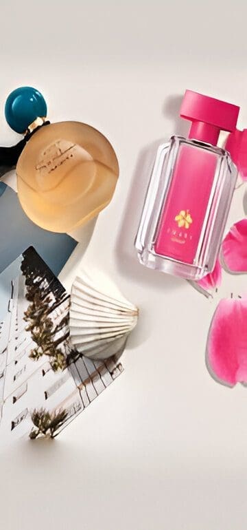 Two perfume bottles beside seashell and photo