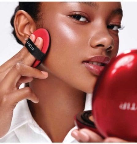 Woman applying makeup with red puff.